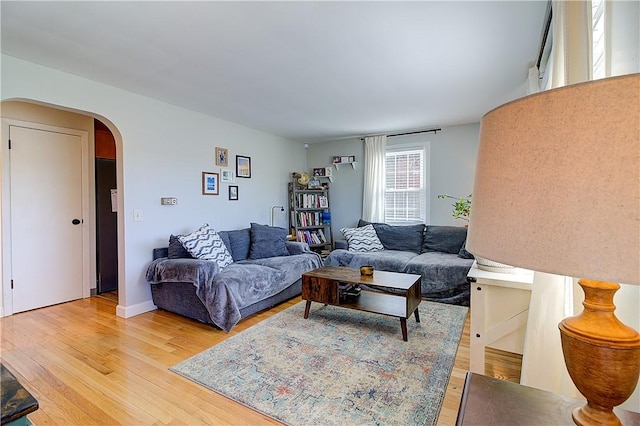 living area featuring arched walkways and light wood-style floors
