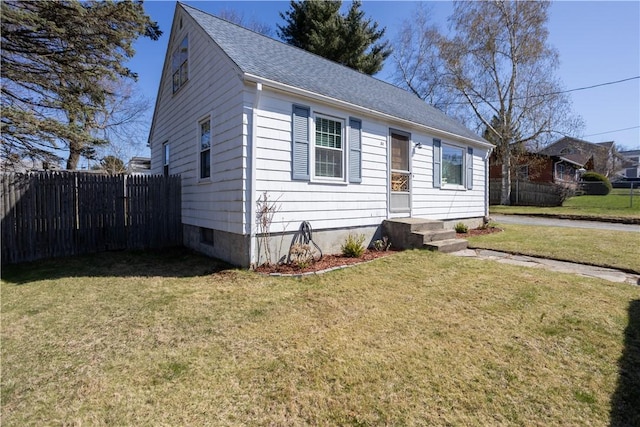 bungalow-style house featuring roof with shingles, fence, and a front lawn