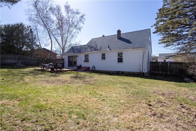 back of house featuring a chimney, fence, and a lawn