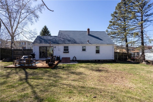 back of property with a shingled roof, a yard, a chimney, fence, and a wooden deck