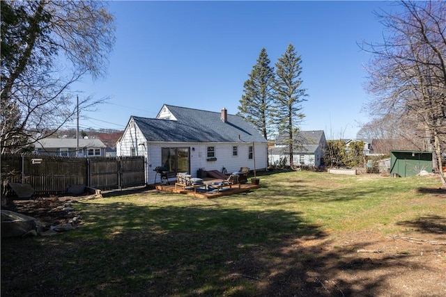 back of property with an outbuilding, a lawn, a storage unit, fence, and a chimney