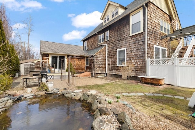55 Hunter Ave, Newport, RI 02840 - back of property featuring fence, a wooden deck, a patio, roof with shingles, and an outdoor structure