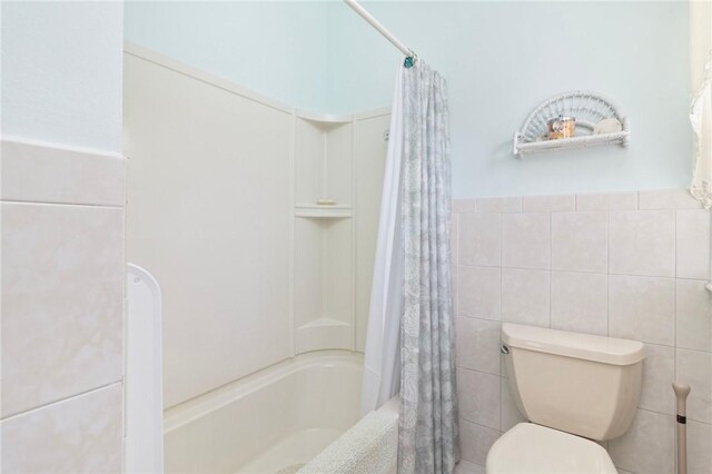 55 Hunter Ave, Newport, RI 02840 - bathroom featuring toilet, shower / bath combo with shower curtain, tile walls, and wainscoting