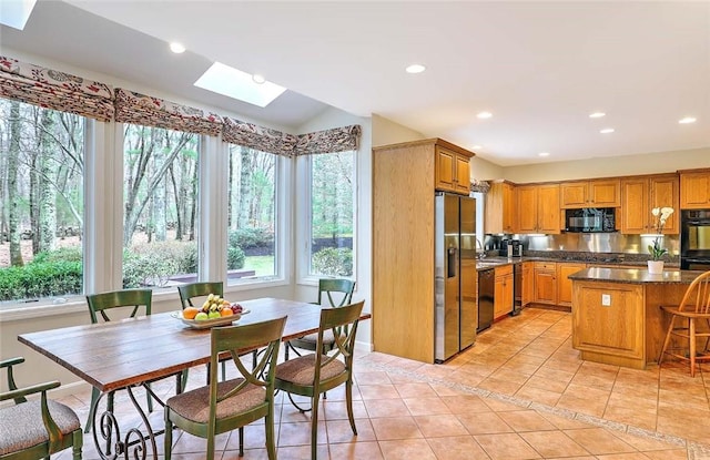 kitchen with a skylight, black appliances, light tile patterned flooring, and a wealth of natural light