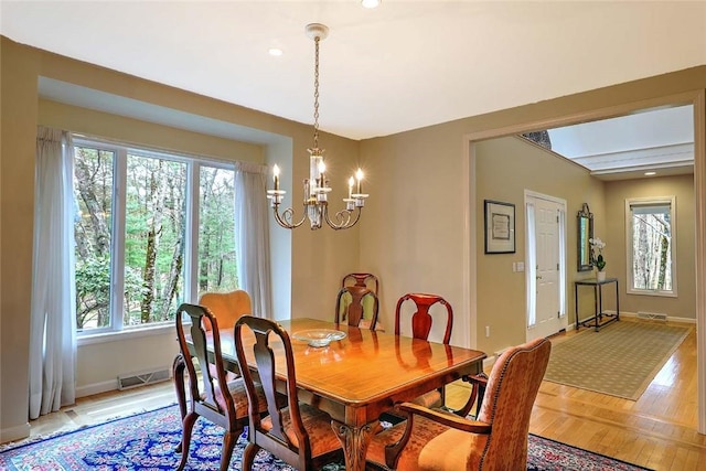 dining room featuring baseboards, plenty of natural light, a chandelier, and visible vents