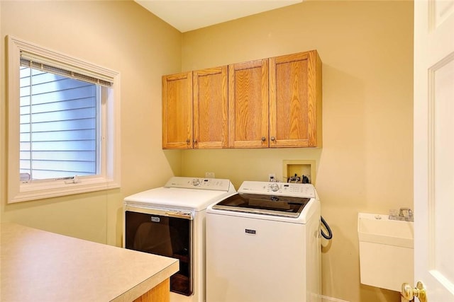 washroom featuring a sink, washing machine and dryer, and cabinet space