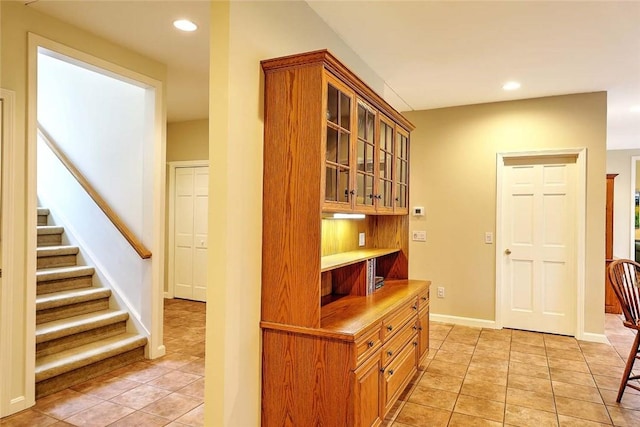 hallway featuring light tile patterned floors, baseboards, recessed lighting, and stairs