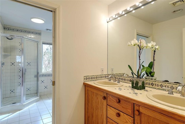 full bathroom with double vanity, visible vents, a shower stall, a sink, and tile patterned floors