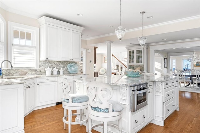 7 Fenway Rd, Westerly, RI 02891 - kitchen with decorative columns, light wood finished floors, white cabinetry, and a sink