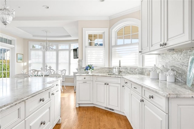 7 Fenway Rd, Westerly, RI 02891 - kitchen featuring light wood-style flooring, white cabinetry, a notable chandelier, and a sink