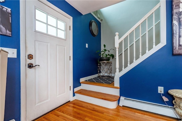 entryway featuring stairway, a baseboard heating unit, and wood finished floors