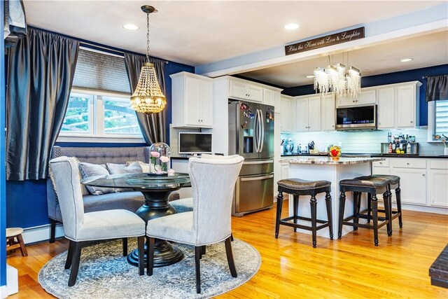 dining area with light wood-style flooring, a chandelier, and baseboard heating