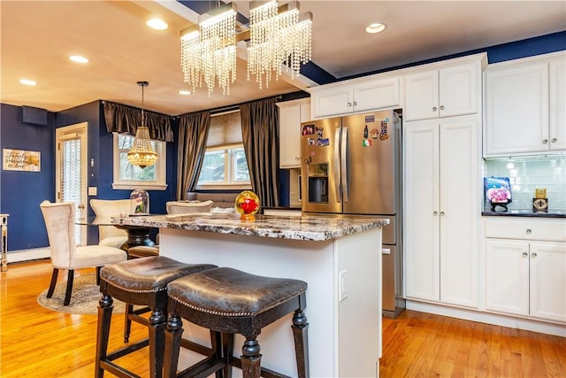 kitchen featuring a center island, white cabinets, light wood-type flooring, and stainless steel fridge