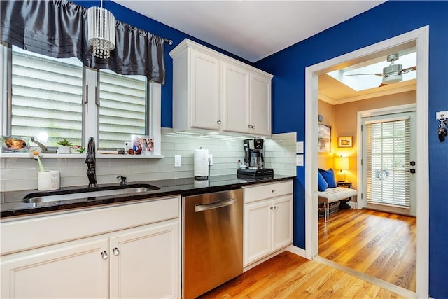 kitchen featuring light wood-style flooring, tasteful backsplash, white cabinets, dishwasher, and a sink