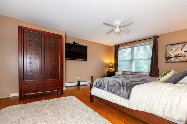 bedroom with baseboard heating, wood finished floors, and ceiling fan