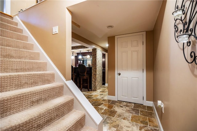 stairway with baseboards and stone finish floor