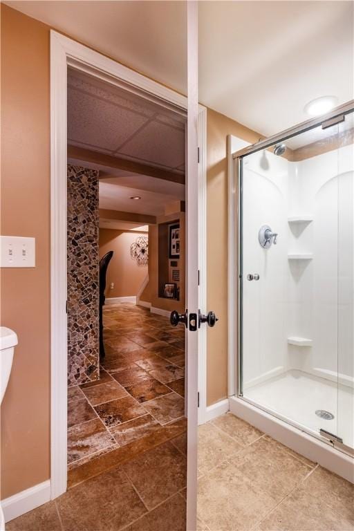 bathroom with baseboards, stone finish floor, and a stall shower