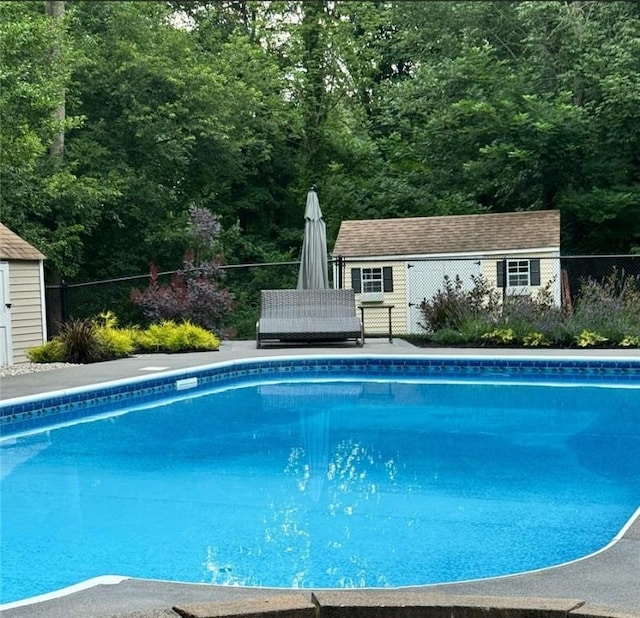 pool featuring a storage unit, fence, and an outdoor structure