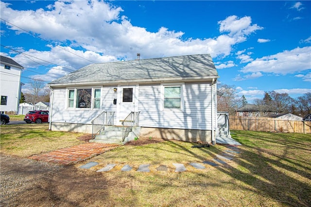 view of front of property with roof with shingles, fence, and a front lawn