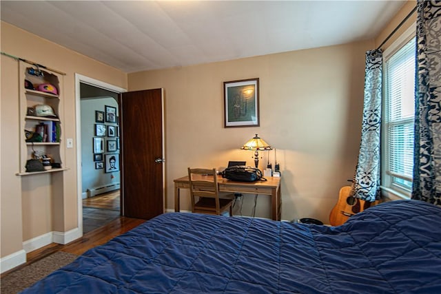bedroom with baseboards, multiple windows, wood finished floors, and baseboard heating
