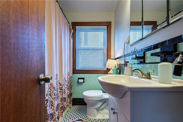 bathroom with vanity, wainscoting, tile walls, and toilet