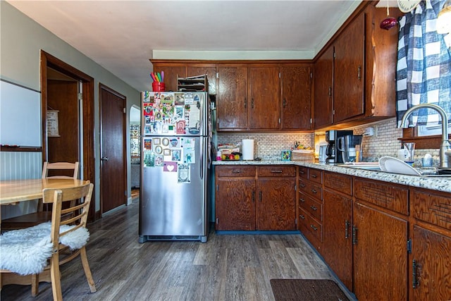 kitchen with freestanding refrigerator, wood finished floors, a sink, light countertops, and decorative backsplash