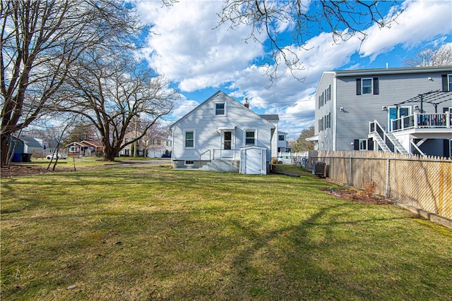 rear view of property with a yard, fence, and cooling unit