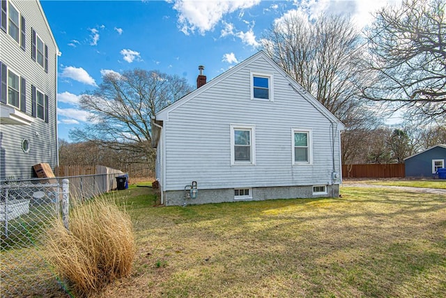 view of side of home featuring a yard, fence, and a chimney