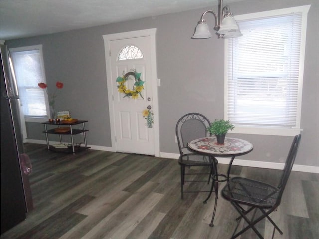 dining space with baseboards, wood finished floors, and a chandelier