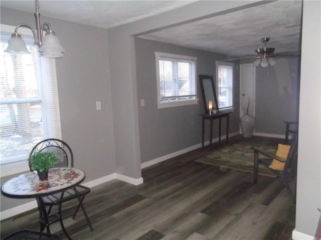 interior space with baseboards, dark wood-style flooring, and ceiling fan with notable chandelier