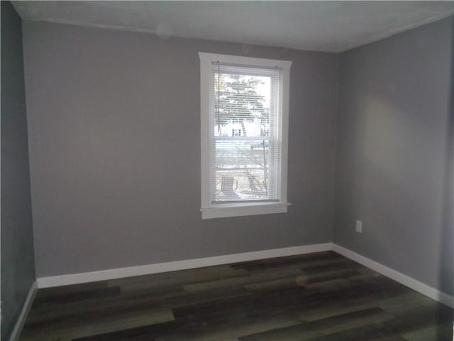 empty room featuring baseboards and dark wood-type flooring