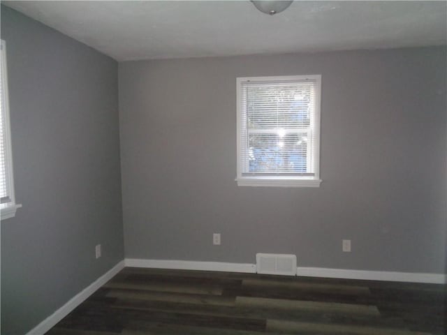 spare room featuring dark wood-type flooring, baseboards, and visible vents