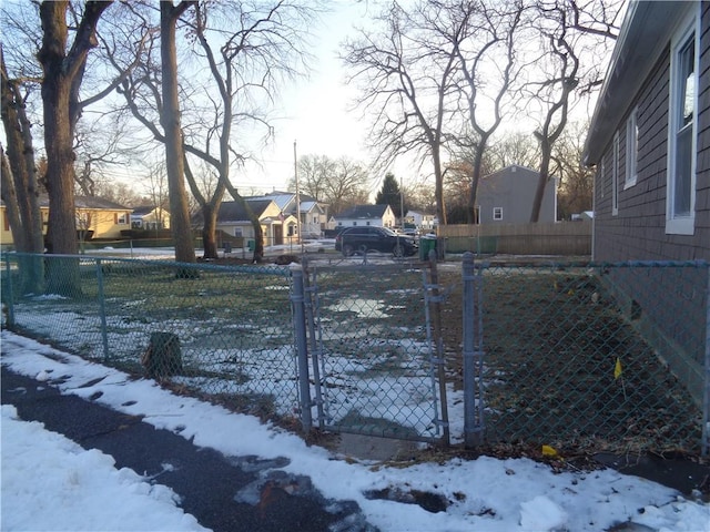 yard layered in snow with fence and a residential view