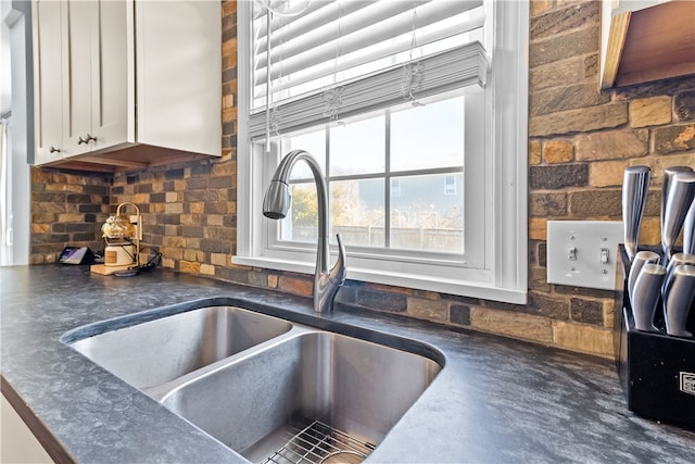 interior details featuring dark countertops, white cabinets, backsplash, and a sink