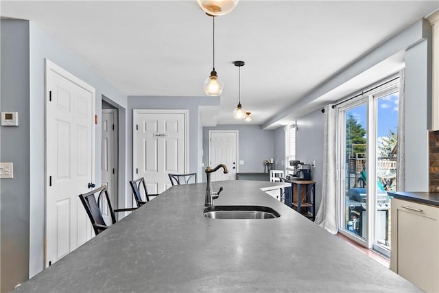 kitchen featuring hanging light fixtures, a sink, and dark countertops