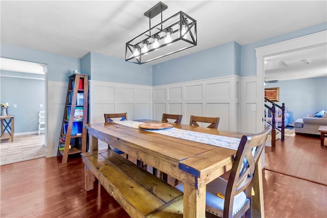 dining space with a wainscoted wall, wood finished floors, and a decorative wall