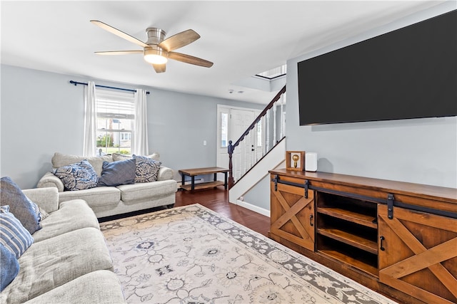 living area with stairway, ceiling fan, and dark wood-type flooring