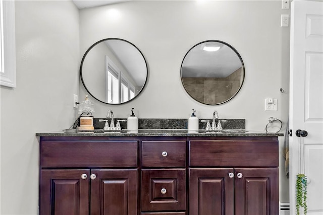 bathroom with double vanity, a sink, and a baseboard heating unit
