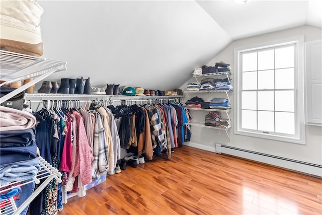 walk in closet with lofted ceiling, wood finished floors, and baseboard heating