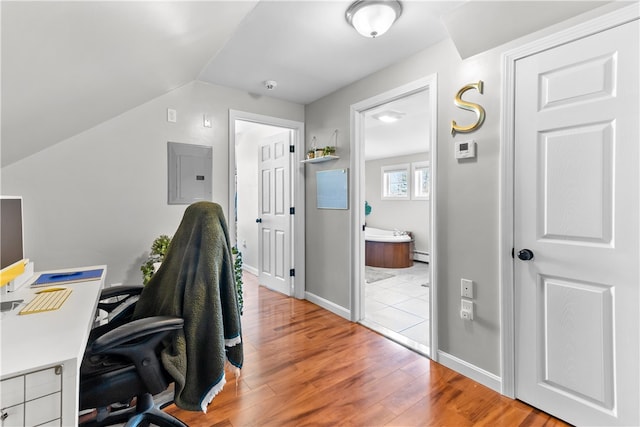 office featuring electric panel, lofted ceiling, baseboard heating, baseboards, and wood finished floors