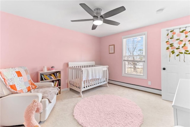 carpeted bedroom featuring baseboards, a nursery area, ceiling fan, and baseboard heating