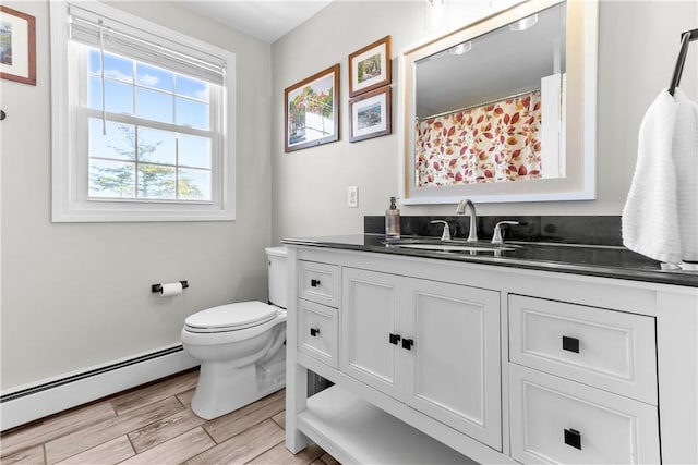 bathroom featuring toilet, a baseboard heating unit, vanity, and wood finished floors