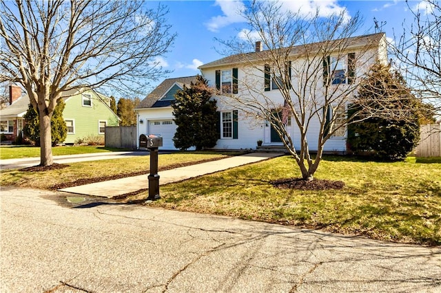 view of front of house with fence, driveway, a front lawn, a garage, and a chimney