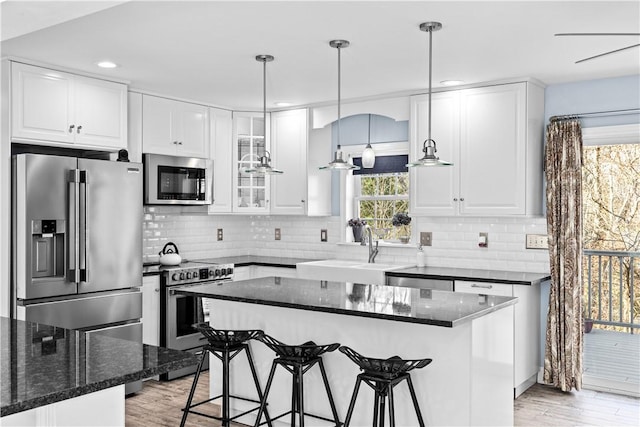 5 Nottingham Way, Freetown, MA 02702 - kitchen featuring stainless steel appliances, a sink, a kitchen breakfast bar, light wood-style flooring, and white cabinets