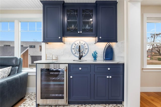 bar with tasteful backsplash, baseboards, beverage cooler, indoor wet bar, and wood finished floors