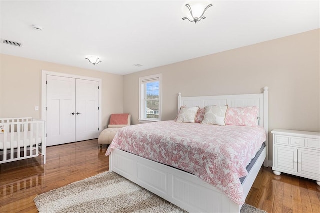 bedroom with wood finished floors, a closet, and visible vents