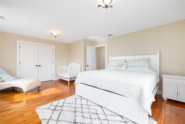 bedroom featuring baseboards, visible vents, a closet, and wood finished floors