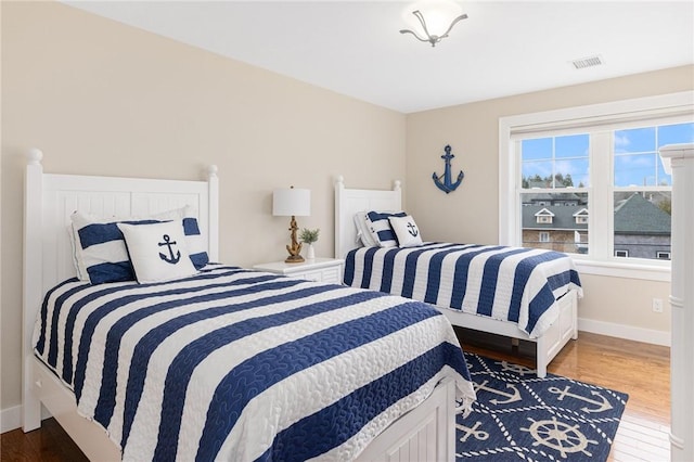 bedroom featuring visible vents, baseboards, and wood finished floors