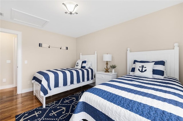 bedroom featuring baseboards, attic access, and wood finished floors