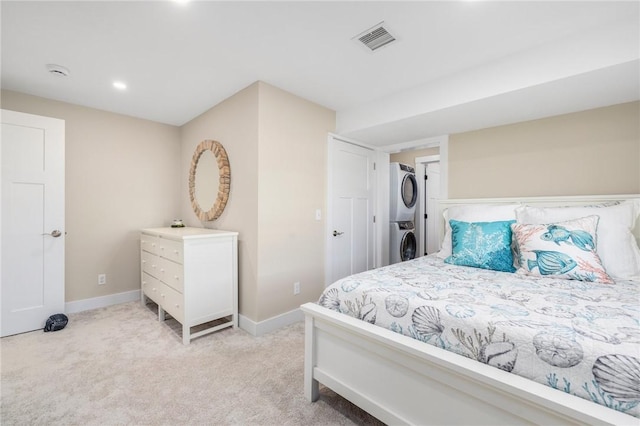bedroom featuring stacked washer and clothes dryer, light carpet, baseboards, and visible vents
